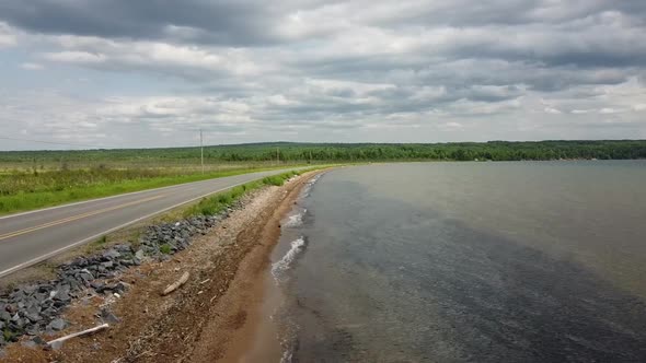 Aerial Along Road Next to Lake with Waves and Dark Clouds