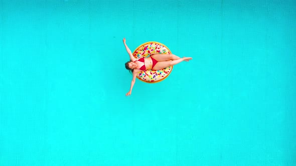 Aerial View of a Woman in Red Bikini Swimming on a Donut in the Pool