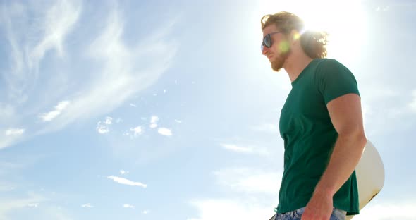 Man with sand board shielding his eyes in the desert