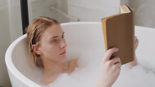 Young Woman Reading Book in Bath