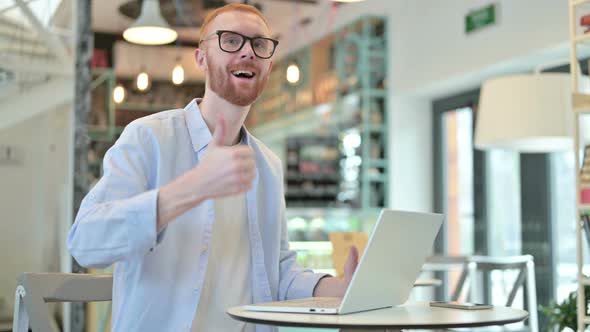 Thumbs Up By Redhead Man with Laptop in Cafe 