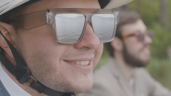 Close-up Face of Confident Young Man in Sunglasses and Helmet Smiling in Slow Motion. Portrait of