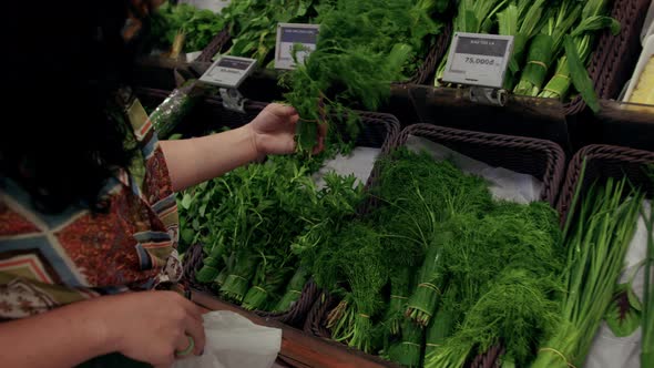 Young Woman Housewife in a Grocery Store Buys Green Onions and Dill Groceries a Young Woman Chooses