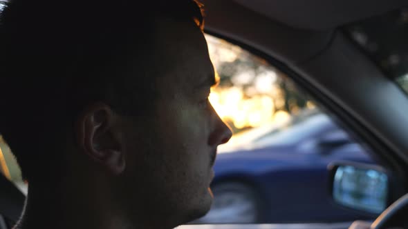 Profile of Handsome Man Driving Car Through Countryside at Sunset Time
