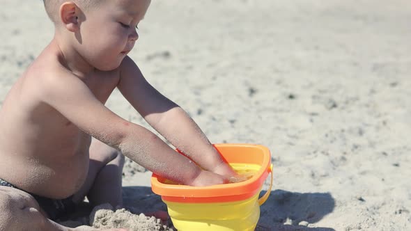 Little Baby Boy Child Playing on Beach Filling Bucket Seawater Running on Sand