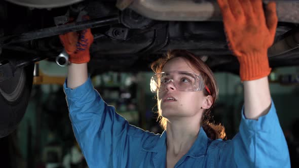 Portrait of a Female Mechanic Working Under a Vehicle in a Car Service