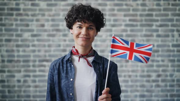 Slow Motion Portrait of Attractive Lady Holding British Flag on Brick Background