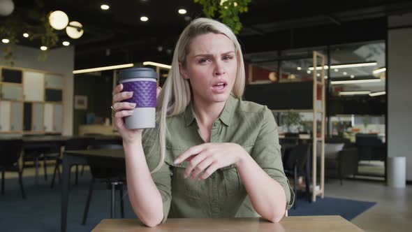 Caucasian businesswoman having a video chat drinking a cup of coffee in modern office