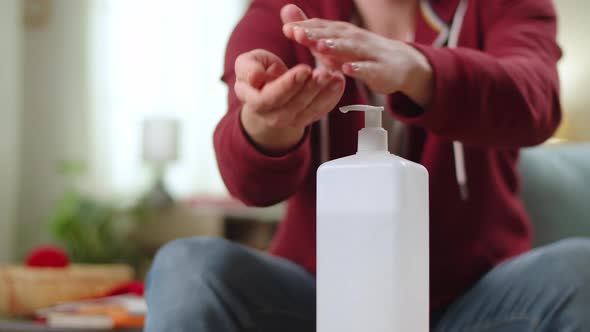 A Man Uses a Sanitizer to Disinfect the Hands at Home in the Living Room