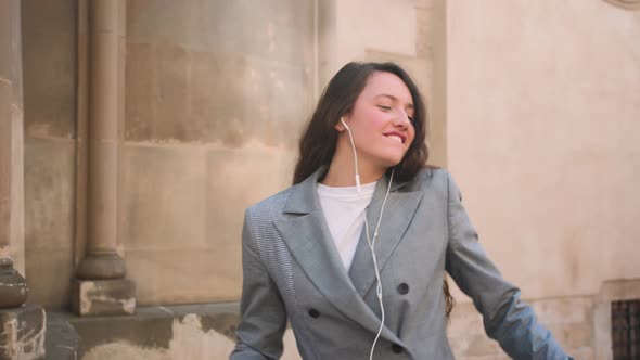 Woman in Headphones Earphones Listening to Music in the Street and Dancing