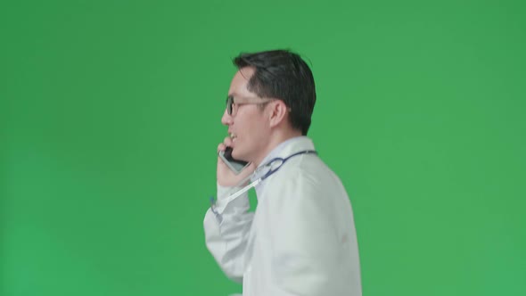 Side View Of Asian Doctor With Stethoscope Talking On Mobile Phone While Running On Green Screen