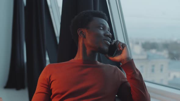 Afro-American Man Speaking on Phone by Window in Office