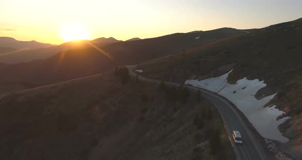 White Cargo Van or Bus Driving Down the Mountain Road at Sunset Time