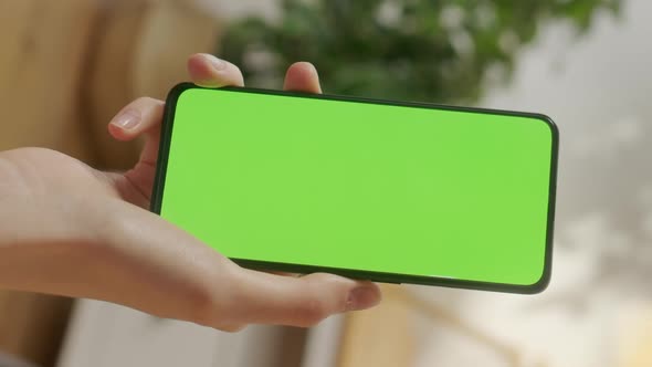 Back View of Woman Holding Chroma Key Green Screen Smartphone Watching Content Without Touching or