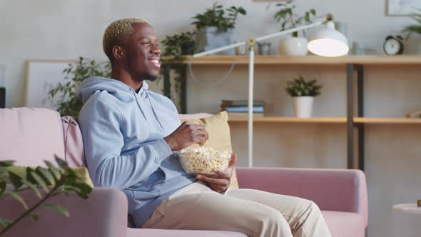 Black Man Eating Popcorn and Watching Comedy Movie at Home
