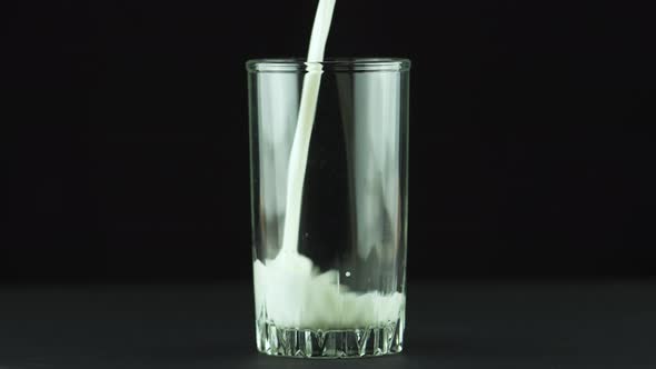 Milk Pouring Into Glass Close Up Isolated on Black Background