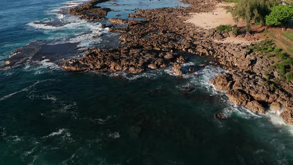 Aerial tilt up shot flying low over snorkelers and swimmers in Shark Cove along O'ahu's North Shore