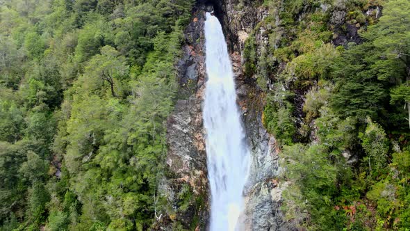 Aerial orbit of the Rio Blanco waterfall surrounded by the forest of Hornopiren National Park, Chile