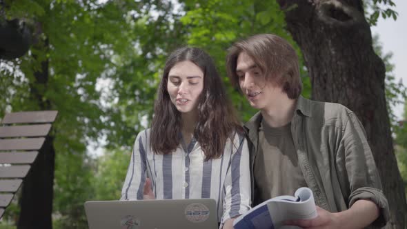 Portrait Happy Couple Spending Time Together in the Park, Studying. The Male and Female Students in