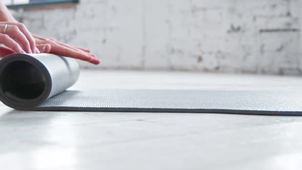 Woman hands roll grey rubber mat