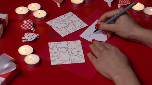 Women's Hands Write Love You on a Valentine Love Card