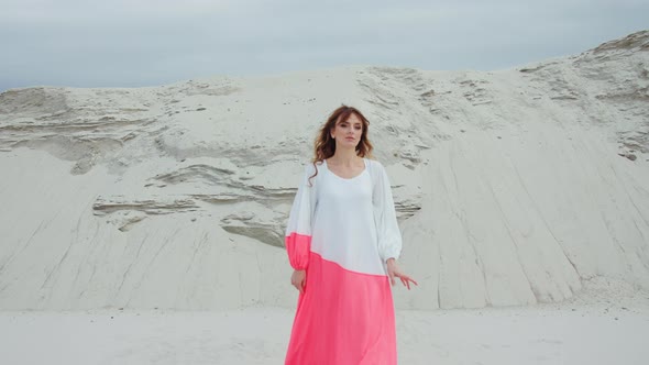 Model Woman in Dress Walking on the Sand Smiling at Camera Stones in the Background