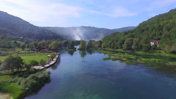 Aerial view of beautiful Una river in Bosnia with smoke rising in the background