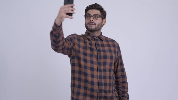 Happy Young Bearded Indian Hipster Man Taking Selfie with Phone