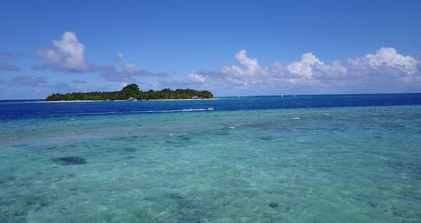 Wide fly over copy space shot of a white sand paradise beach and aqua blue ocean background in 4K