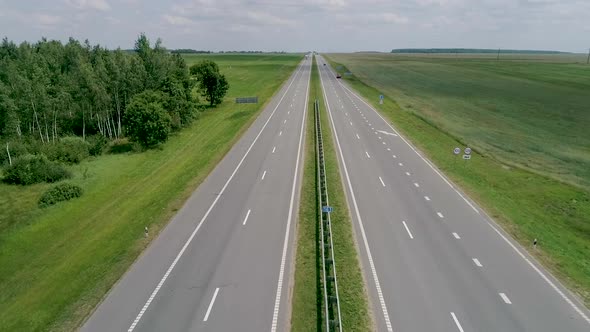 A Long Highway Through a Forest Area. Car Trip. Drone Top View