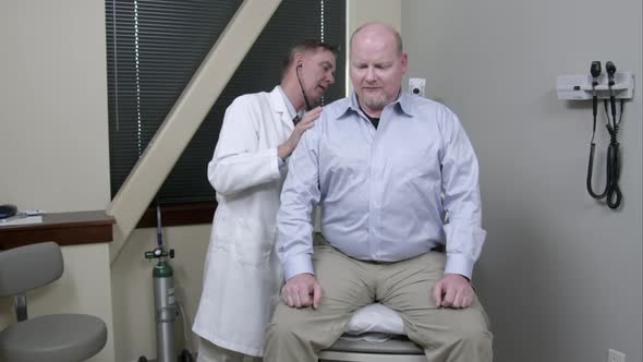 Doctor with stethescope checking man's breathing and heart rate.