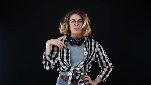 Serious Young Woman in Black and White Plaid Shirt and Headphones on Neck Doing NO Gesture