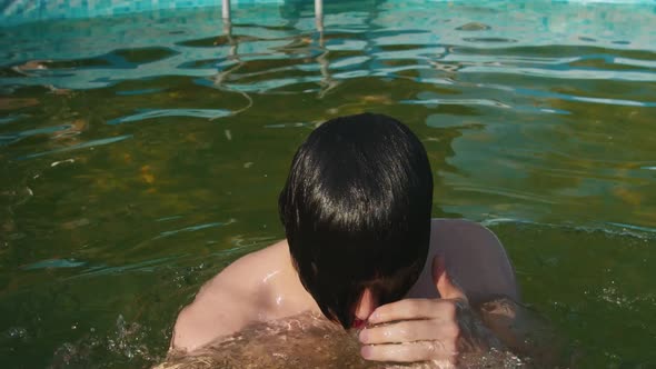 Young Man Jumping Out of the Water and Removes the Hair Off the Face