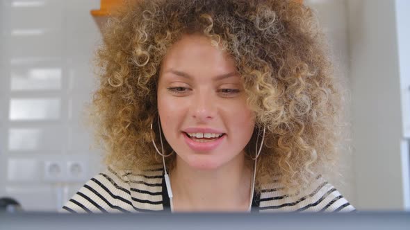 Cheerful young white female with curly hair talking on web camera while wearing headset in 4k video