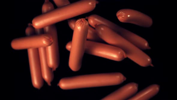 Super Slow Motion Sausages Rise Up Against a Black Background