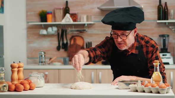 Man Sieving Flour Over Dough on Table
