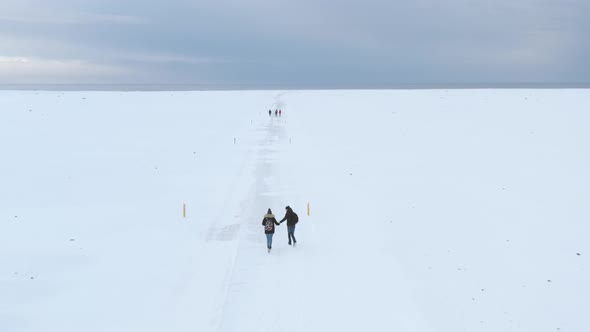 Group of Travelers Friends Walking on a Snow Desert in Iceland at Winter
