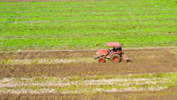 A Farmer Uses a Tractor To Prepare the Soil for Rice Cultivation