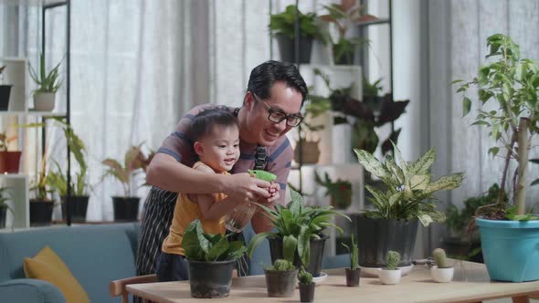Happy Asian Man With Son Watering Plants At Home
