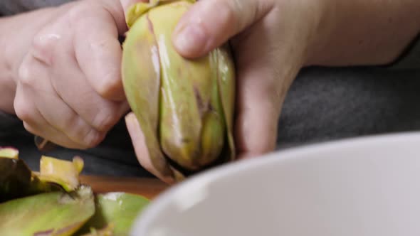 Woman Cleaning Artichokes with Knife