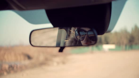 Woman Look On Car Mirror Before Driving. Girl In Sunglasses Reflected In Rearview Mirror.