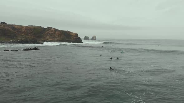 Aerial Drone shot going forward over Surfers on a cold day at the sea, Pichilemu, Chile-4K