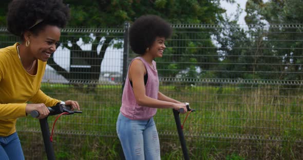 Two mixed race women riding electric scooter