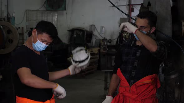 Workers taking off hat, wiping sweat, and talking to each other