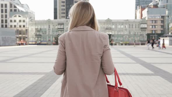 Business Woman Walks Across the Square in a Big City