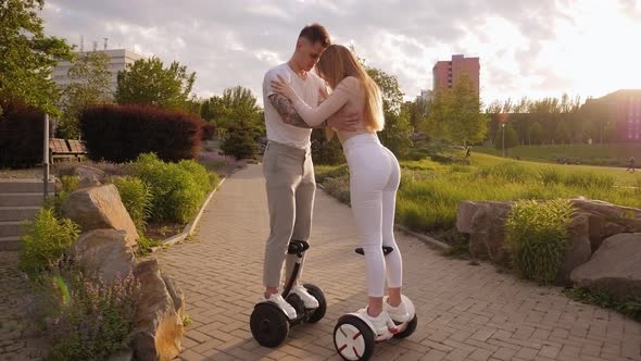 A Young Sports Couple Rides a Gyro Scooter in a Beautiful Park in the Summer.