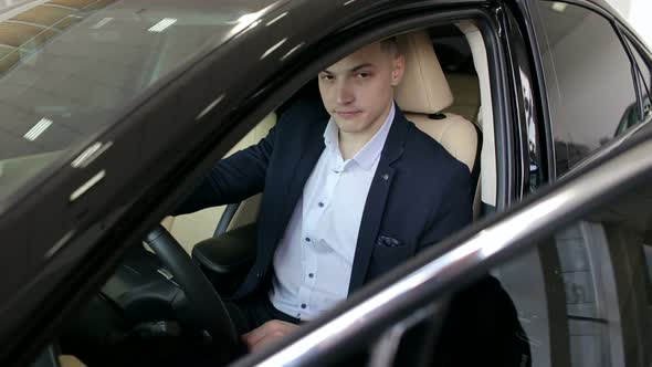 A Successful Self-confident Man Chooses a New Car in the Showroom