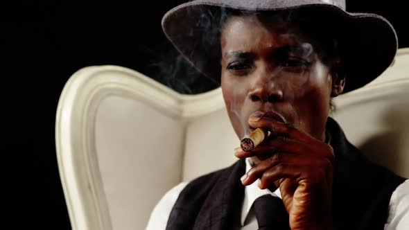 Androgynous man smoking cigar on armchair