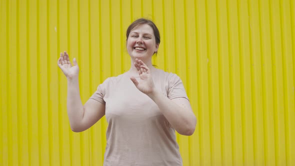 Portrait of Caucasian Simple Woman Dancing Against Bright Yellow Ribbed Wall