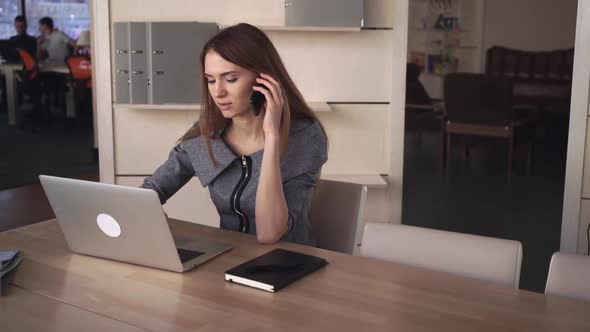 Businesswoman Using Mobile Phone in the Office To Commmunicate with a Call Receiver